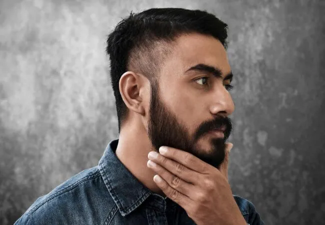 Profile view of a man with a full, closely trimmed beard.